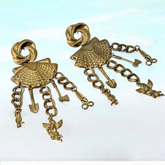 Vintage 1980s French stamped brass dangle earrings featuring a scallop shell centerpiece with eclectic dangling charms, including an owl, shovel, putti angel, axe, and scissors. Unique statement jewelry with a bold boho style, rich patina, and artistic character.