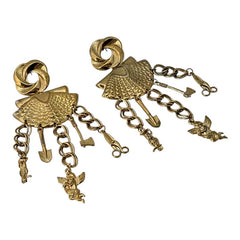 Vintage 1980s French stamped brass dangle earrings featuring a scallop shell centerpiece with eclectic dangling charms, including an owl, shovel, putti angel, axe, and scissors. Unique statement jewelry with a bold boho style, rich patina, and artistic character.