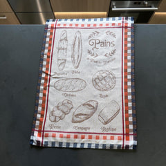 French jacquard cotton tea towel in beige, orange, and blue featuring illustrations of traditional French breads with “Pains de Tradition Française” lettering. Made in France.