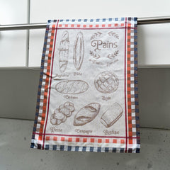 French jacquard cotton tea towel in beige, orange, and blue featuring illustrations of traditional French breads with “Pains de Tradition Française” lettering. Made in France.