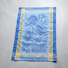 French jacquard cotton tea towel in sky blue and golden yellow featuring woven sunflower design and ornate border.