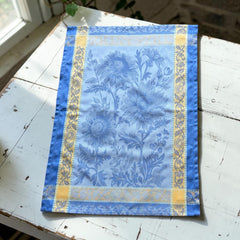 French jacquard cotton tea towel in sky blue and golden yellow featuring woven sunflower design and ornate border.