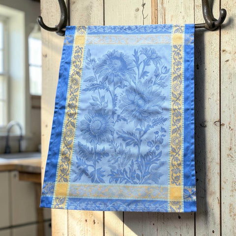 French jacquard cotton tea towel in sky blue and golden yellow featuring woven sunflower design and ornate border.