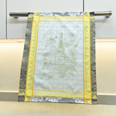 French jacquard cotton tea towel in green, yellow, and soft gray featuring a Le Vieux Chêne wine bottle surrounded by grapes and vine leaves.