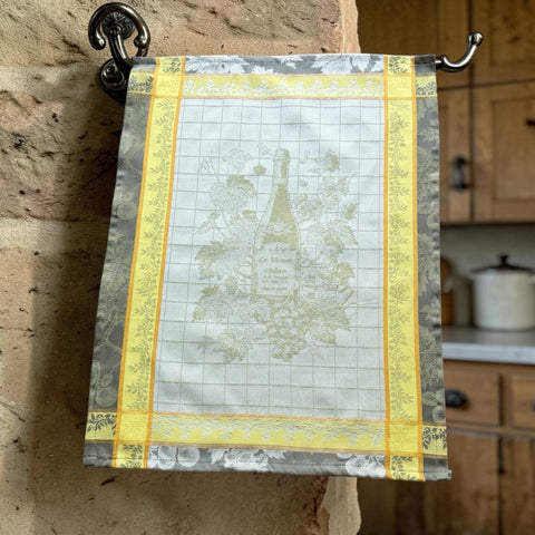 French jacquard cotton tea towel in green, yellow, and soft gray featuring a Le Vieux Chêne wine bottle surrounded by grapes and vine leaves.