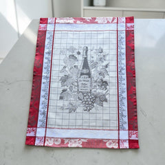 French jacquard cotton tea towel in red, white, and soft gray beige featuring a Le Vieux Chêne wine bottle surrounded by grapes and vine leaves.