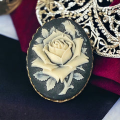 A lovely vintage French faux cameo scarf/dress clip from the late 1950s or early 1960s. Featuring a cream-colored high relief rose set against a black background, encased in a scalloped gold-tone bezel. The hammered gold frame adds texture, while the clip at the back ensures secure attachment to scarves, dresses, or lapels. Marked '3S' on the back, though the maker is unknown. A timeless and elegant accessory, perfect for vintage lovers and sustainable fashion enthusiasts.