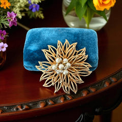 Vintage 1960s gold-tone floral brooch with openwork textured petals, featuring faux pearls and clear rhinestones on headpins at the center.