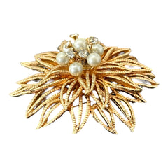 Vintage 1960s gold-tone floral brooch with openwork textured petals, featuring faux pearls and clear rhinestones on headpins at the center.