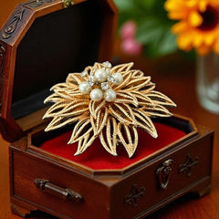 Vintage 1960s gold-tone floral brooch with openwork textured petals, featuring faux pearls and clear rhinestones on headpins at the center.