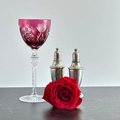 Vintage cranberry cut crystal goblet with geometric star and fan cuts, faceted clear stem, and round foot.