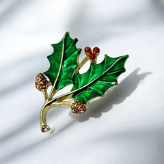 Vintage Gerry’s holly brooch with red enamel berries and metallic green enamel leaves on a gold-tone stem; signed Gerry’s on the back, 1980s holiday jewelry in very good condition with minor enamel wear.