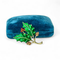 Vintage Gerry’s holly brooch with red enamel berries and metallic green enamel leaves on a gold-tone stem; signed Gerry’s on the back, 1980s holiday jewelry in very good condition with minor enamel wear.
