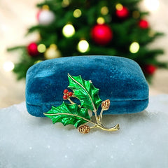 Vintage Gerry’s holly brooch with red enamel berries and metallic green enamel leaves on a gold-tone stem; signed Gerry’s on the back, 1980s holiday jewelry in very good condition with minor enamel wear.