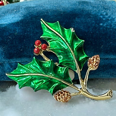 Vintage Gerry’s holly brooch with red enamel berries and metallic green enamel leaves on a gold-tone stem; signed Gerry’s on the back, 1980s holiday jewelry in very good condition with minor enamel wear.