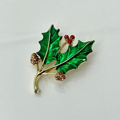 Vintage Gerry’s holly brooch with red enamel berries and metallic green enamel leaves on a gold-tone stem; signed Gerry’s on the back, 1980s holiday jewelry in very good condition with minor enamel wear.