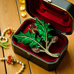 Vintage Gerry’s holly brooch with red enamel berries and metallic green enamel leaves on a gold-tone stem; signed Gerry’s on the back, 1980s holiday jewelry in very good condition with minor enamel wear.