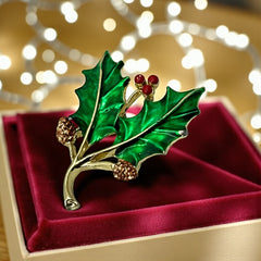 Vintage Gerry’s holly brooch with red enamel berries and metallic green enamel leaves on a gold-tone stem; signed Gerry’s on the back, 1980s holiday jewelry in very good condition with minor enamel wear.