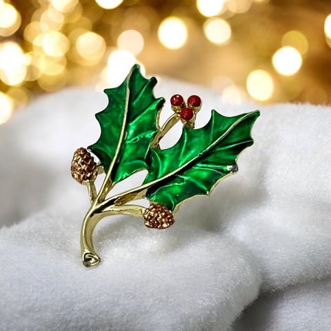 Vintage Gerry’s holly brooch with red enamel berries and metallic green enamel leaves on a gold-tone stem; signed Gerry’s on the back, 1980s holiday jewelry in very good condition with minor enamel wear.
