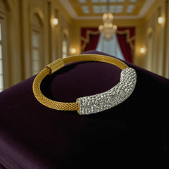 Gold tone mesh bracelet with a curved white centerpiece set with clear rhinestones over silver foil backing, creating a bright silvery shimmer; finished with a magnetic clasp and sleek modern design.