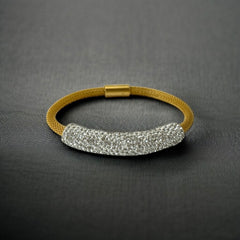 Gold tone mesh bracelet with a curved white centerpiece set with clear rhinestones over silver foil backing, creating a bright silvery shimmer; finished with a magnetic clasp and sleek modern design.