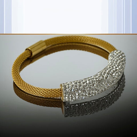 Gold tone mesh bracelet with a curved white centerpiece set with clear rhinestones over silver foil backing, creating a bright silvery shimmer; finished with a magnetic clasp and sleek modern design.