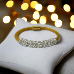 Gold tone mesh bracelet with a curved white centerpiece set with clear rhinestones over silver foil backing, creating a bright silvery shimmer; finished with a magnetic clasp and sleek modern design.