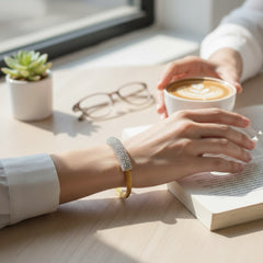 Gold tone mesh bracelet with a curved white centerpiece set with clear rhinestones over silver foil backing, creating a bright silvery shimmer; finished with a magnetic clasp and sleek modern design.