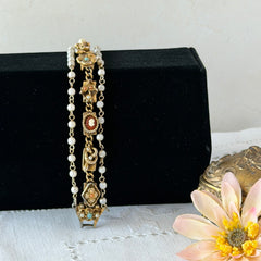 Vintage Goldette NY Victorian Revival bracelet with faux pearls, floral and animal motifs, cameo, and gold‑tone links showing gentle patina.