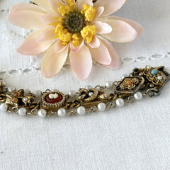Vintage Goldette NY Victorian Revival bracelet with faux pearls, floral and animal motifs, cameo, and gold‑tone links showing gentle patina.