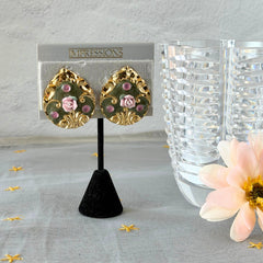 Vintage 1980s teardrop post earrings with 3D pink polymer clay rose, green enamel base, and gold tone pressed metal scrollwork on original card.