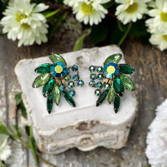 Vintage 1960s clip-on floral earrings with green and iridescent rhinestones in chaton, navette, and marquise cuts, set in gold-tone metal—sparkling midcentury costume jewelry in very good condition.
