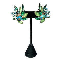 Vintage 1960s clip-on floral earrings with green and iridescent rhinestones in chaton, navette, and marquise cuts, set in gold-tone metal—sparkling midcentury costume jewelry in very good condition.
