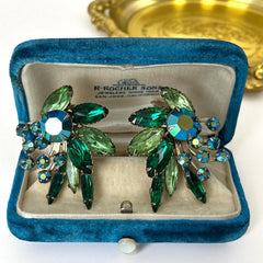 Vintage 1960s clip-on floral earrings with green and iridescent rhinestones in chaton, navette, and marquise cuts, set in gold-tone metal—sparkling midcentury costume jewelry in very good condition.