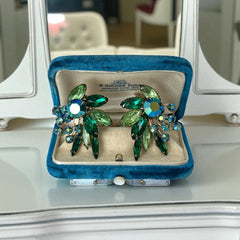 Vintage 1960s clip-on floral earrings with green and iridescent rhinestones in chaton, navette, and marquise cuts, set in gold-tone metal—sparkling midcentury costume jewelry in very good condition.