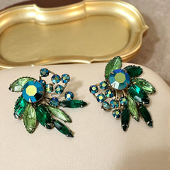Vintage 1960s clip-on floral earrings with green and iridescent rhinestones in chaton, navette, and marquise cuts, set in gold-tone metal—sparkling midcentury costume jewelry in very good condition.