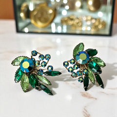 Vintage 1960s clip-on floral earrings with green and iridescent rhinestones in chaton, navette, and marquise cuts, set in gold-tone metal—sparkling midcentury costume jewelry in very good condition.