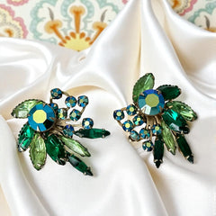 Vintage 1960s clip-on floral earrings with green and iridescent rhinestones in chaton, navette, and marquise cuts, set in gold-tone metal—sparkling midcentury costume jewelry in very good condition.