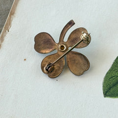 Vintage green guilloché enamel four‑leaf clover brooch with faux pearl center and rose gold tone finish.