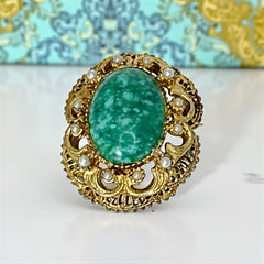 Vintage brooch pendant with mottled green glass cabochon, faux pearls, and ornate gold tone filigree, photographed front and back to highlight its 1960s–70s revival style and dual-wear functionality.