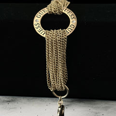 Gold tone Guess bracelet with multi-strand chains and a central ring engraved with ‘GUESS’ and accented by clear rhinestones, shown on neutral backdrop.