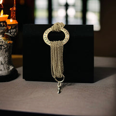 Gold tone Guess bracelet with multi-strand chains and a central ring engraved with ‘GUESS’ and accented by clear rhinestones, shown on neutral backdrop.