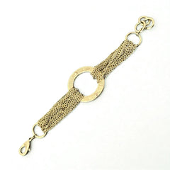 Gold tone Guess bracelet with multi-strand chains and a central ring engraved with ‘GUESS’ and accented by clear rhinestones, shown on neutral backdrop.