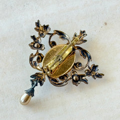 Vintage white guilloché enamel brooch with pink rose motif, faux pearls, and ornate antiqued gold tone filigree frame with teardrop pearl accent.