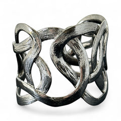 Textured dark silver tone cuff bracelet with interwoven, ribbon-like bands forming a sculptural openwork design; hammered finish adds depth and dimension to the modern, unsigned piece.