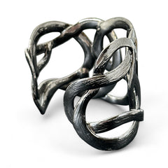 Textured dark silver tone cuff bracelet with interwoven, ribbon-like bands forming a sculptural openwork design; hammered finish adds depth and dimension to the modern, unsigned piece.