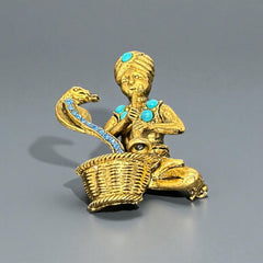 Vintage Hattie Carnegie snake charmer brooch with turquoise cabochons and blue rhinestones, gold tone metal, signed with copyright mark, 1960s figural costume jewelry.