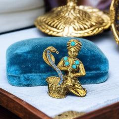 Vintage Hattie Carnegie snake charmer brooch with turquoise cabochons and blue rhinestones, gold tone metal, signed with copyright mark, 1960s figural costume jewelry.