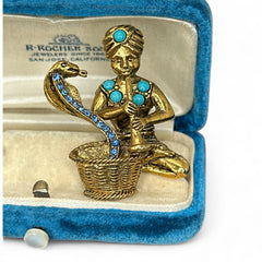 Vintage Hattie Carnegie snake charmer brooch with turquoise cabochons and blue rhinestones, gold tone metal, signed with copyright mark, 1960s figural costume jewelry.
