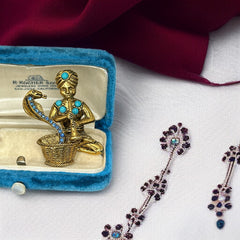 Vintage Hattie Carnegie snake charmer brooch with turquoise cabochons and blue rhinestones, gold tone metal, signed with copyright mark, 1960s figural costume jewelry.